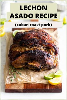 a large piece of meat sitting on top of a cutting board next to lemon wedges