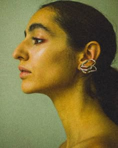 a woman with large earrings on her ear looking off to the side, in profile