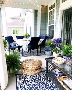 an outdoor patio with blue and white rugs, wicker furniture and potted plants