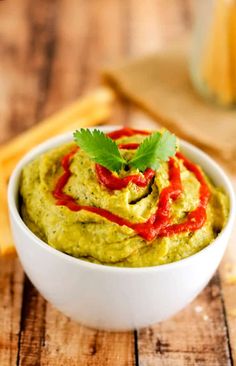 a white bowl filled with guacamole and garnished with cilantro