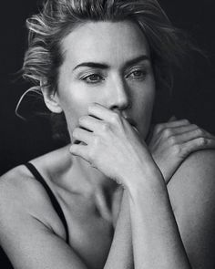 a black and white photo of a woman with her hands on her chin looking at the camera