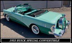 an old green convertible car parked in front of a building with its hood up and the top down