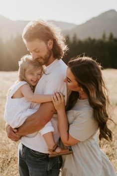 a man and woman holding a child in a field