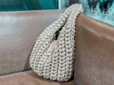 a crocheted purse sitting on the back of a leather couch next to a wall