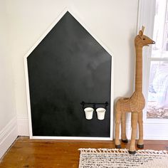 a giraffe statue sitting next to a cup holder in a room with white walls