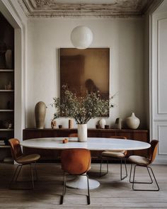 a dining room table with chairs and vases on it