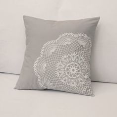 a gray and white pillow sitting on top of a couch