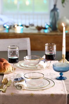 a table set for two with plates, glasses and bread on the plate next to it