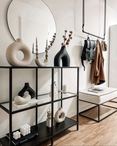 a shelf with vases, mirrors and other items on it in a room that has white walls