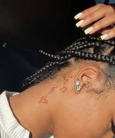 a woman with braids on her head has a small tattoo on her left ear