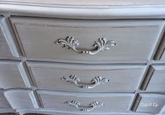 a white dresser with ornate handles and drawers