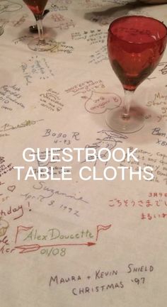 two wine glasses sitting on top of a table covered in handwritten guest book tablescloths