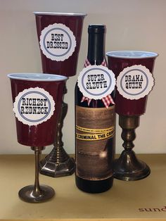 three wine glasses with labels on them sitting next to a bottle