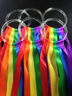 several rainbow colored ribbons tied to each other on a black background with clear acrylic rings