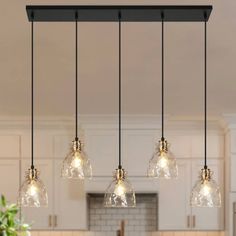 an image of a kitchen light fixture with clear glass shades hanging over the counter top