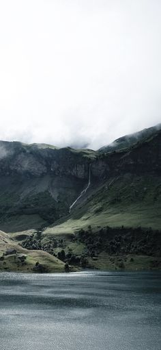 a lake surrounded by mountains under a cloudy sky