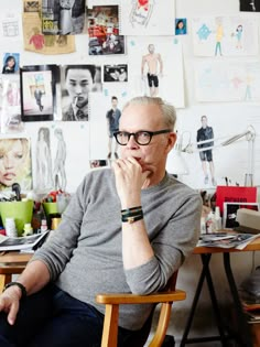 an older man sitting in a chair with his hand on his chin and looking at the camera