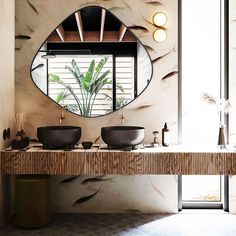 a bathroom with two sinks and a round mirror on the wall above it's counter