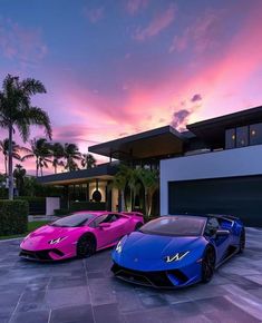 two pink and blue sports cars parked in front of a large house at sunset with palm trees