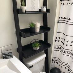 a bathroom with a toilet, sink and shelves above it that have plants on them