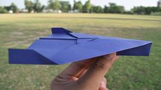 a hand holding up a blue paper airplane