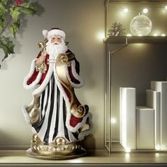 a santa clause figurine sitting on top of a table next to a christmas tree