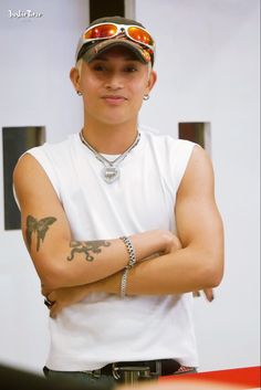 a man with his arms crossed in front of him wearing sunglasses and a white t - shirt