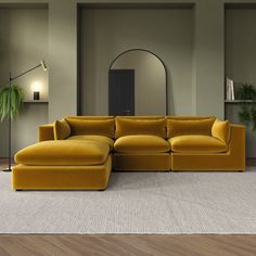 a large yellow couch sitting on top of a wooden floor next to a green plant