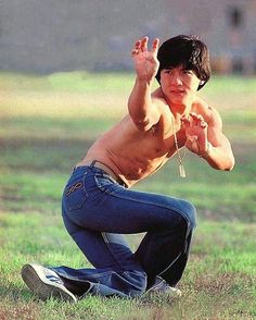 a shirtless young man kneeling on the ground with his hands up in the air