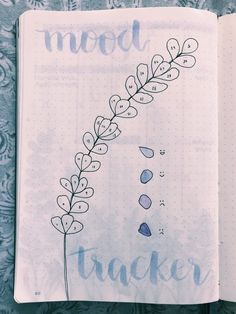 an open notebook with the words mood tracker written in purple ink on top of it