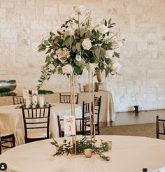 the centerpieces are arranged on top of tables with white flowers and greenery