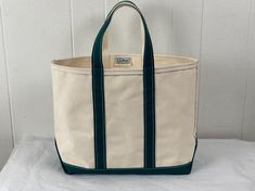 Vintage 1980s(?)  thick natural canvas bag with dark green trim and bottom. L.L. Bean Boat and Tote. Has two handles and one main compartment. Label reads: Made by L. L. Bean Freeport Maine Boat and Tote.  Bag measures  15" wide,  12" tall  6" thick Handles hang down 6" In excellent condition, it looks unused. Green Duck Canvas Travel Bag, Green Canvas Tote Bag With Canvas Lining, Green Duck Canvas Bag For Daily Use, Green Duck Canvas Bag With Canvas Lining, Green Duck Canvas Tote Bag, Vintage Canvas Bags For Errands, Green Cotton Canvas Bag With Leather Handles, Green Canvas Bag With Leather Handles, Everyday Vintage Canvas Bag With Large Capacity