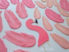 pink flamingo shaped cookies are on a white surface with icing and other decorations