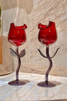 two red glass vases sitting on top of a marble counter