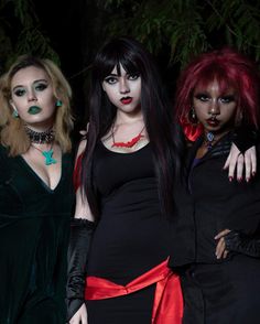 three women dressed in black and red posing for the camera