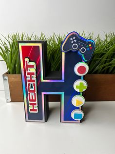 the letter h is made out of cardboard and has a video game controller on it