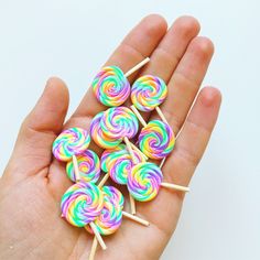 a hand holding several lollipops in it's palm