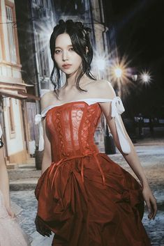 a woman in a red dress is walking down the street with another woman behind her