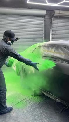 a man painting a car with green paint