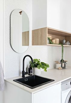 a kitchen sink with a black faucet next to a washer and dryer