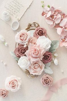 some pink flowers are sitting on a table with ribbons and other things around them,