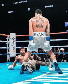 a man laying on the ground in front of a boxing ring with his leg up