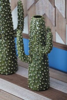 three green cactus shaped vases sitting on top of a wooden shelf next to each other