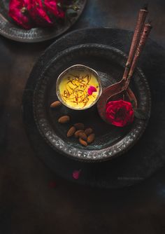 two plates with food on them, one has almonds and the other has rose petals