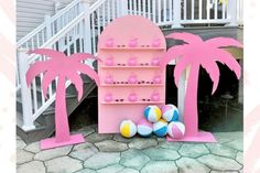 there is a pink shelf with beach balls and palm trees in front of the stairs