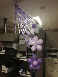 purple and white balloons are hanging from the ceiling in an office cubicle with a computer desk