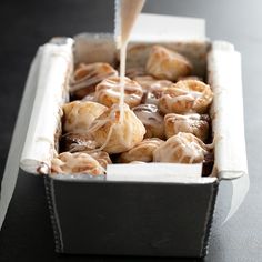 a person pouring icing on some food in a box