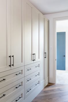 an empty room with white cupboards and wood flooring on the side walk in closet