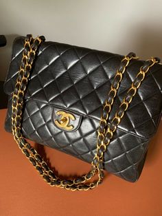 This is an authentic vintage CHANEL jumbo bag in classic black lambskin leather. The gold chain is 24K gold plated which can only be found in vintage pieces. Currently jumbo flaps retails almost $10K! Get it at a fraction of the price. This is a vintage piece and the leather has some scratches but it will patina beautifully over time and blend in. The leather is still soft like butter and you can see the sheen in the picture. Size: 12" X 8.5" X 3.5" Chanel Jumbo, Vintage Chanel, Hand Bags, Flap Bag, Lambskin Leather, Chanel Bag, Chanel Classic, Classic Black, Gold Hardware