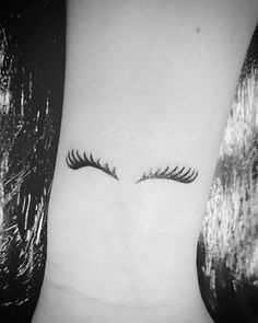 an eye with long lashes on the side of a woman's leg, showing her upper